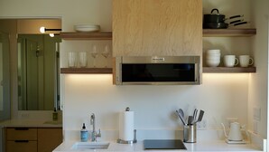 Una cocina moderna con microondas integrado, un lavamanos y armarios de madera.