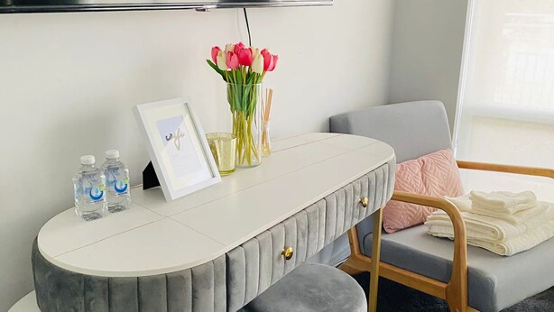 Un salon moderne avec un canapé gris aux lignes courbes, une table basse ronde et un téléviseur à écran plat fixé au mur.