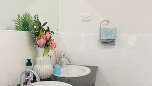 Une salle de bain avec deux lavabos, un miroir, un porte-serviettes et une plante décorative.