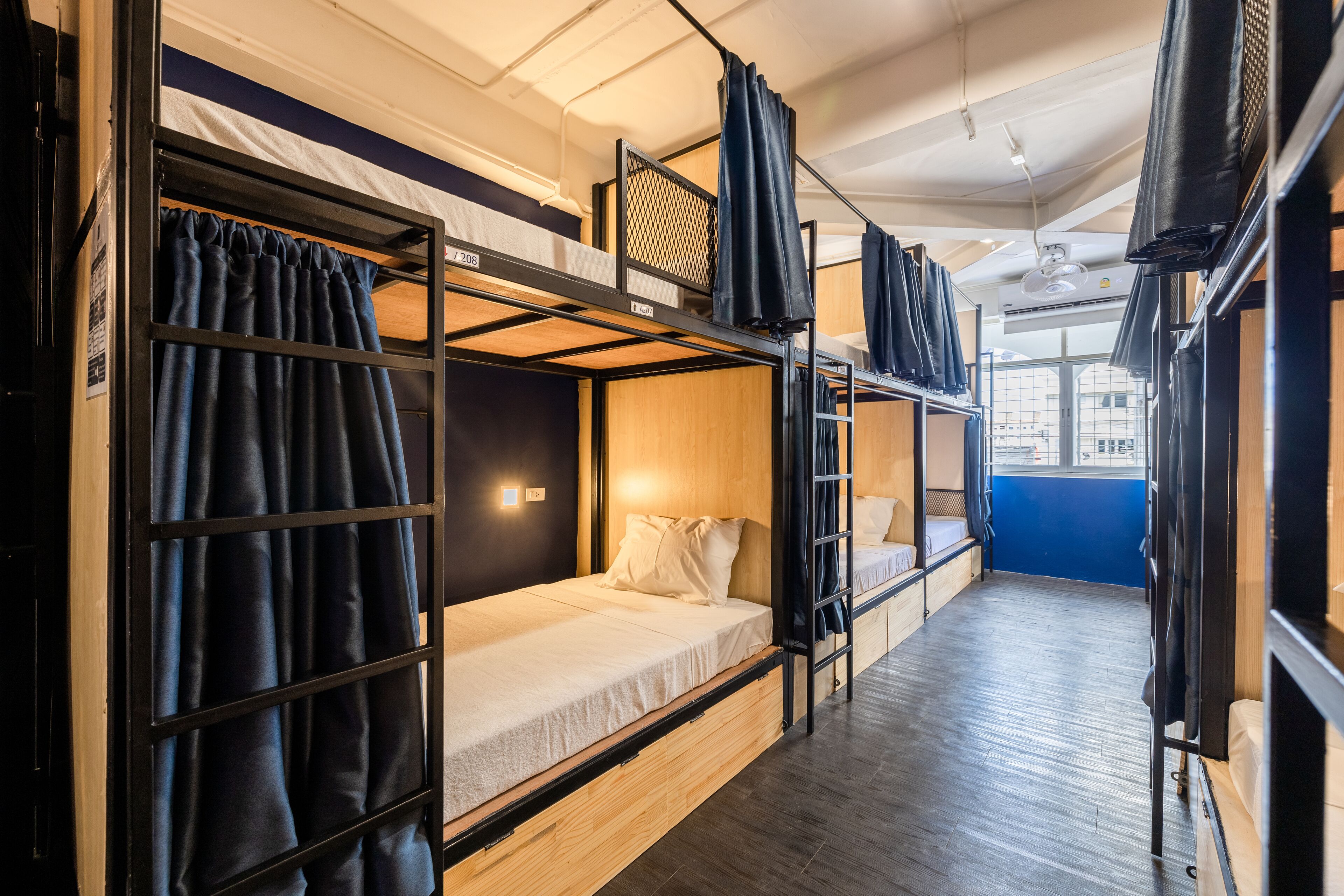 Une chambre de type dortoir, avec des lits superposés, un plancher en bois et une fenêtre laissant entrer la lumière naturelle.