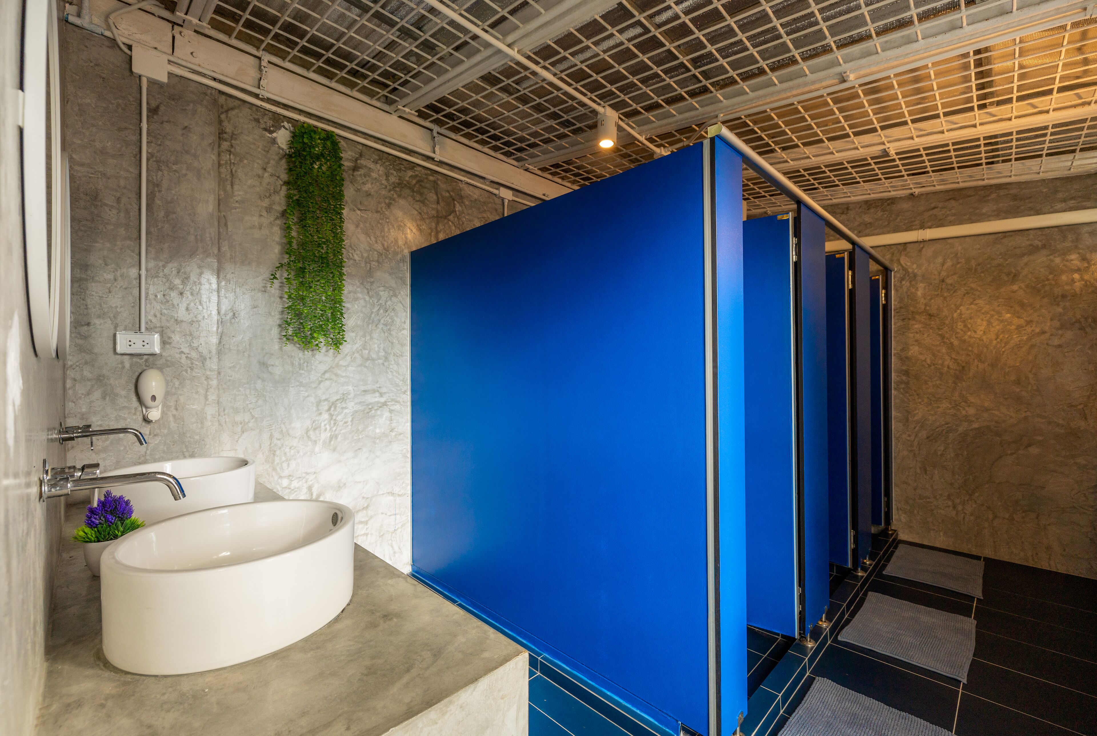 A modern bathroom with a large white sink, a mirror, and a blue partition.