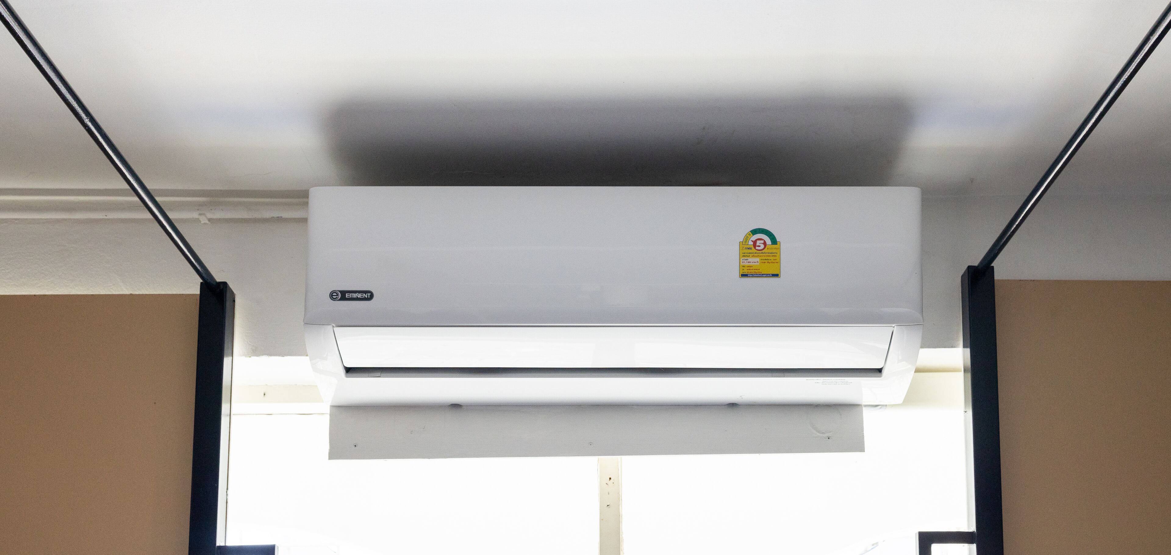 A white air conditioning unit mounted on a wall with a sticker on it.