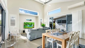 Ein geräumiger Wohnbereich mit grauem Sofa, einem Holzesstisch und einem Deckenventilator.
