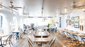 Ein geräumiges Restaurant mit hohen Decken, Holzböden und verschiedenen Sitzgelegenheiten, darunter Tische und Stühle.