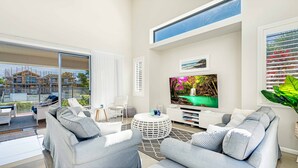 Ein modernes Wohnzimmer mit großem Fernseher, bequemen Sitzmöglichkeiten und Blick auf eine Baustelle.
