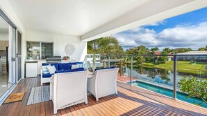 Ein moderner Balkon mit Pool, Essbereich mit Sofa und Tisch sowie eine Küche mit Grill.