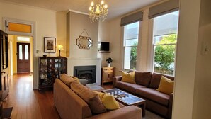 A living room with a fireplace, two sofas, a coffee table, and a chandelier.