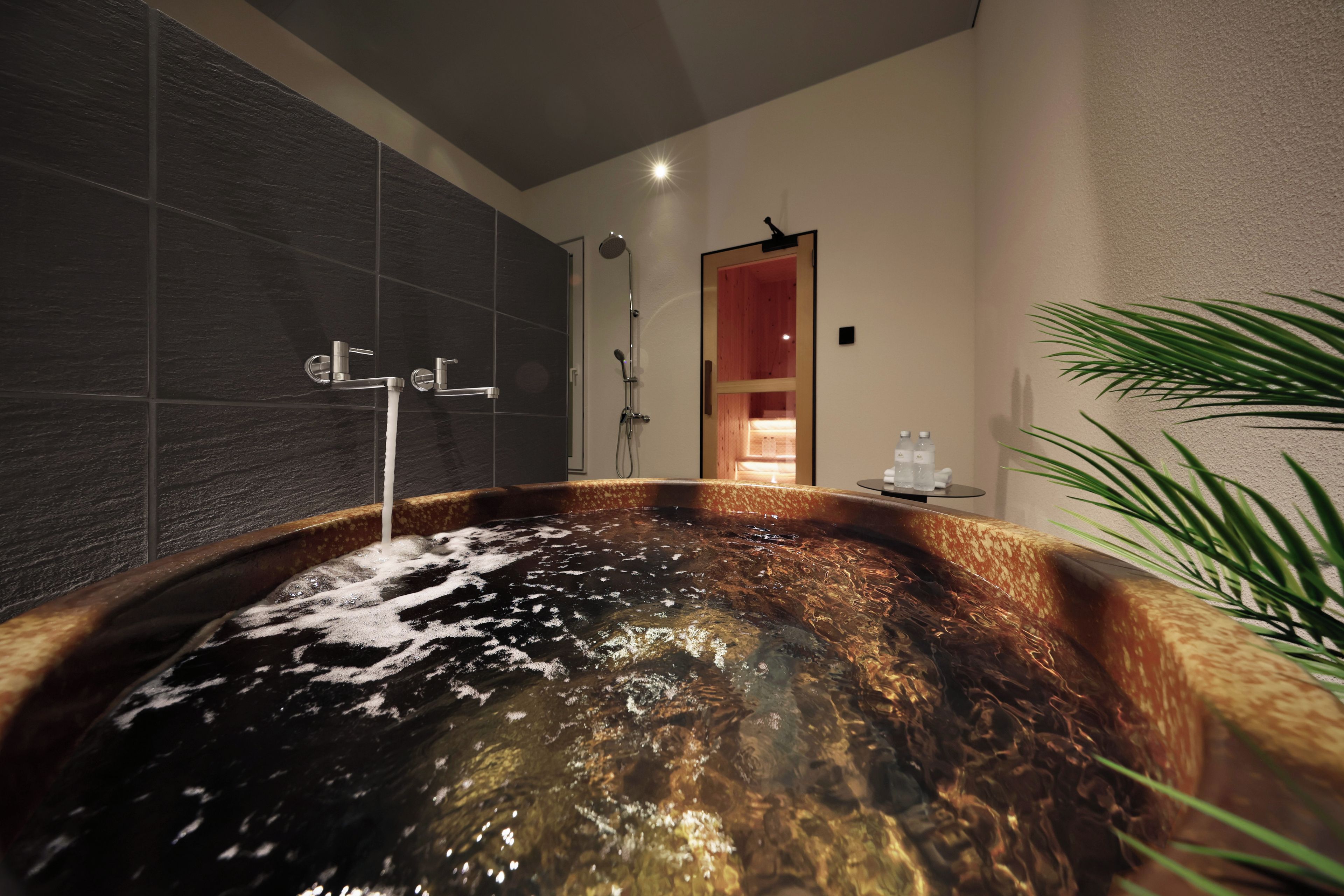 A modern bathroom with a large bathtub, a shower area, and a visible door leading to another room.