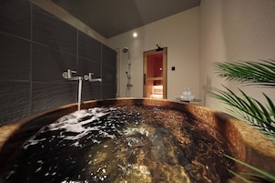 Ein modernes Badezimmer mit einer großen Badewanne, einer Duschkabine und einer sichtbaren Tür zu einem anderen Raum.