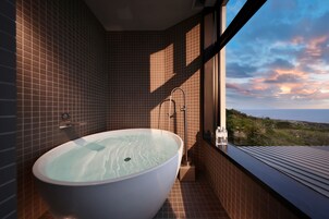 Un baño moderno con una bañera independiente, ducha y vistas al paisaje a través de amplios ventanales.