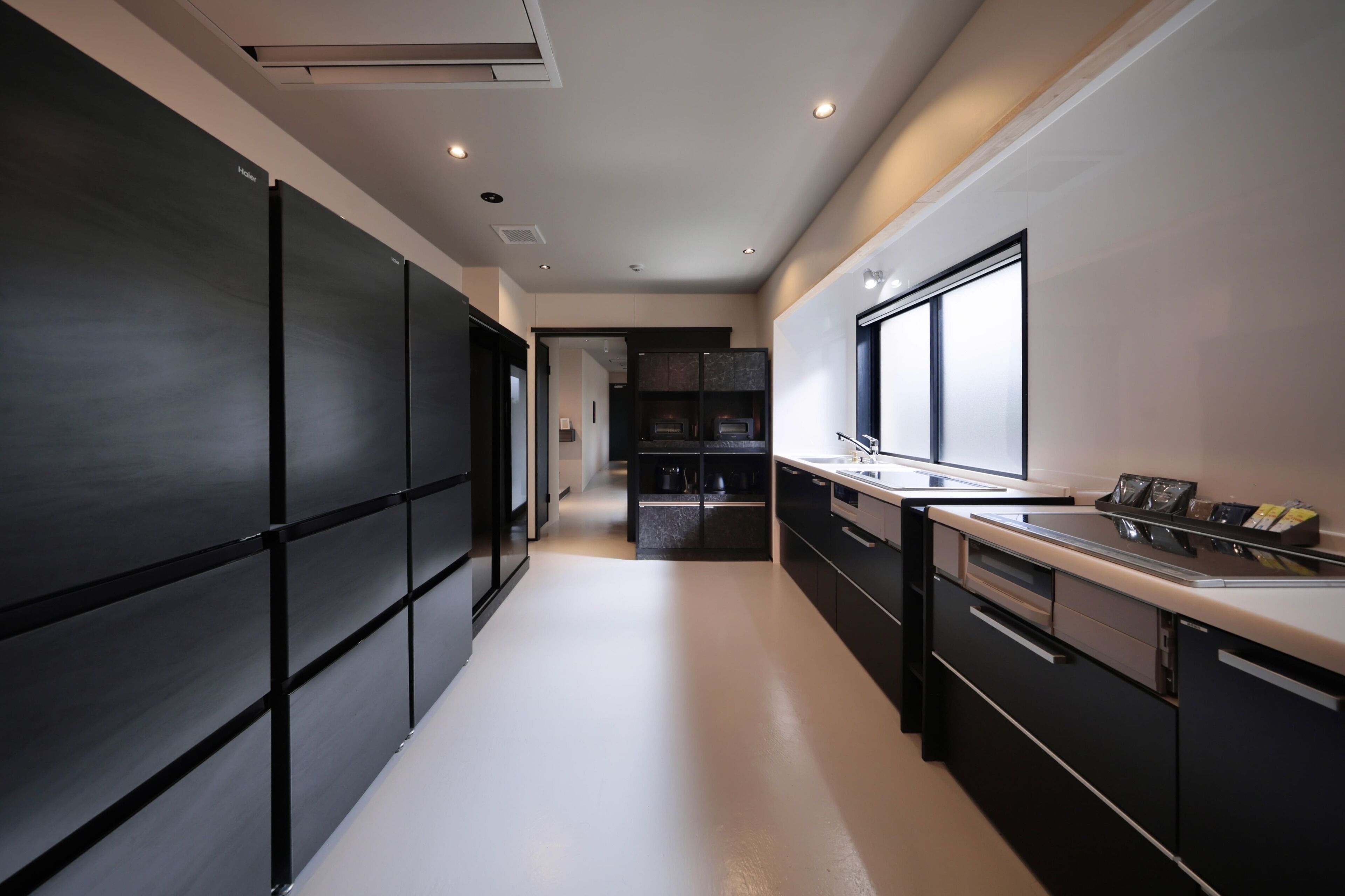 Una cocina moderna con una isla central, muebles negros y un amplio ventanal que proporciona luz natural.