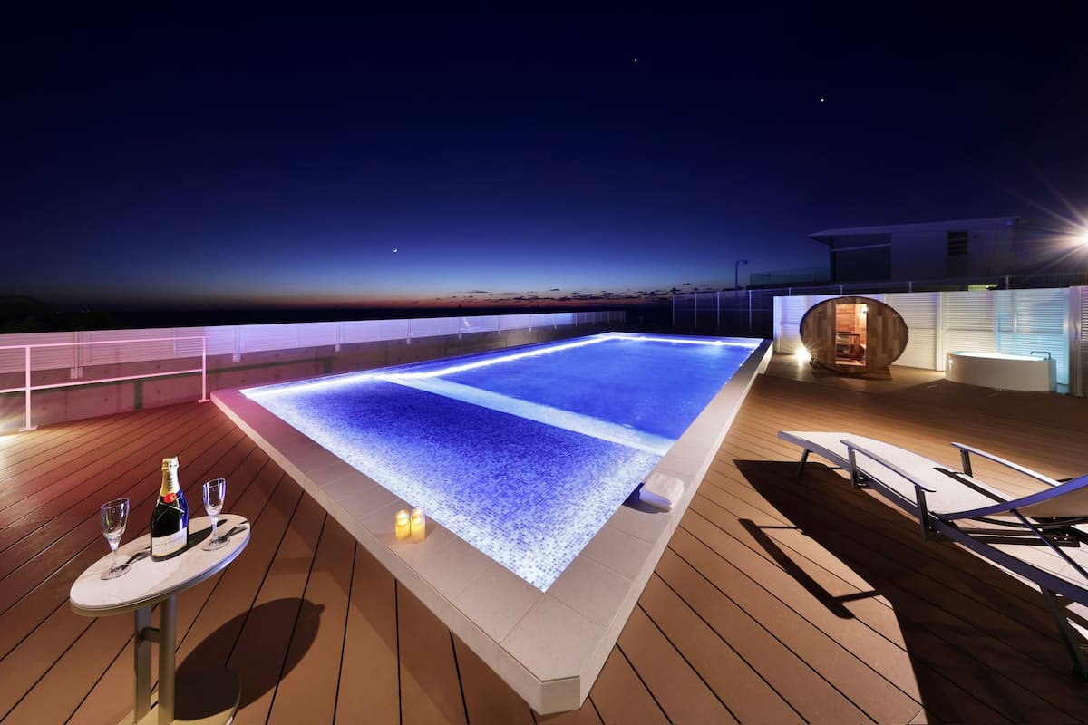 Un espace extérieur agréé avec une piscine chauffée, une table et des chaises, une bouteille de champagne et des bougies.