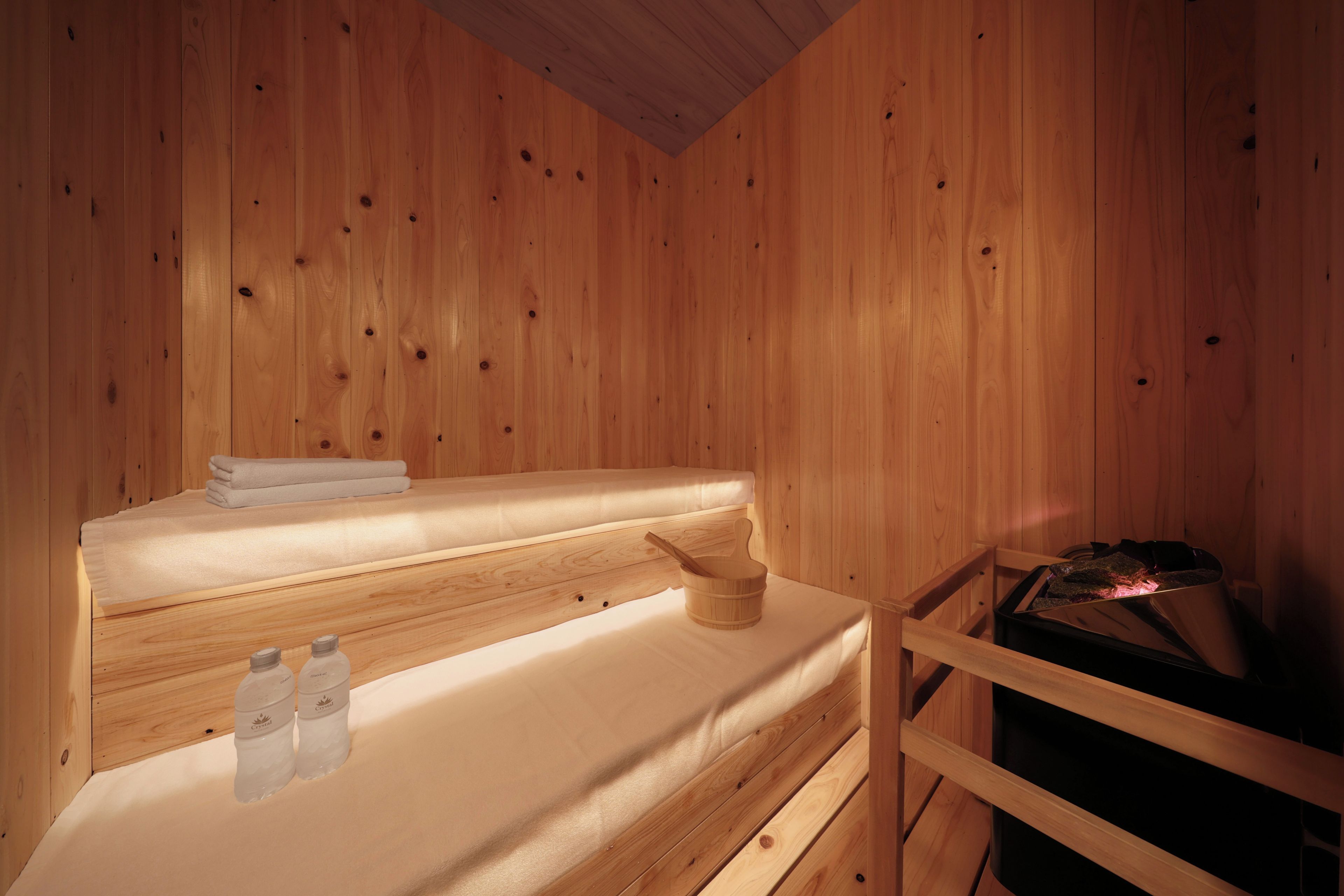 A wooden cabin interior with a bed, a wooden bucket, and a sauna.