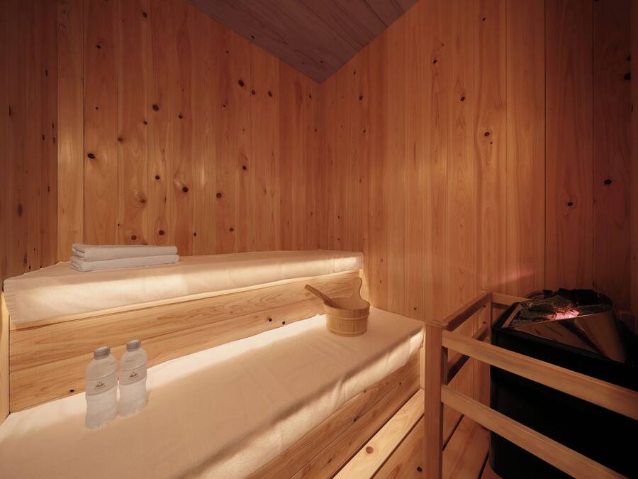 A wooden cabin interior with a bed, a wooden bucket, and a sauna.