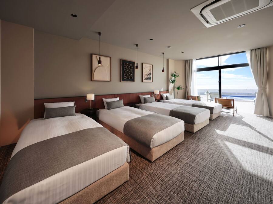 Quarto de hotel com quatro camas, uma janela grande e vista panorâmica, e design moderno.
