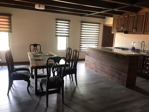 Enjoy meals at the large dining table with six chairs, set against a wall with two windows.