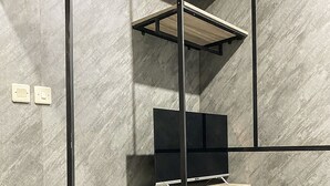 Una habitación moderna con estante para televisión empotrado, cama e interruptor de luz en la pared.
