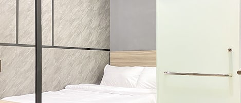 Un dormitorio moderno con cama, mesita de noche, separador de vidrio y unidad de aire acondicionado.