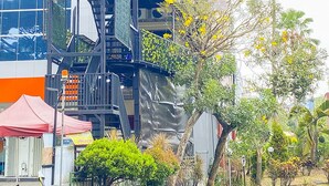 Un edificio moderno con una escalera, una carpa roja y varias plantas.