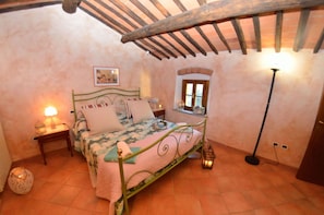 Quarto com cama, mesa de cabeceira, luminária, janela e abajur.