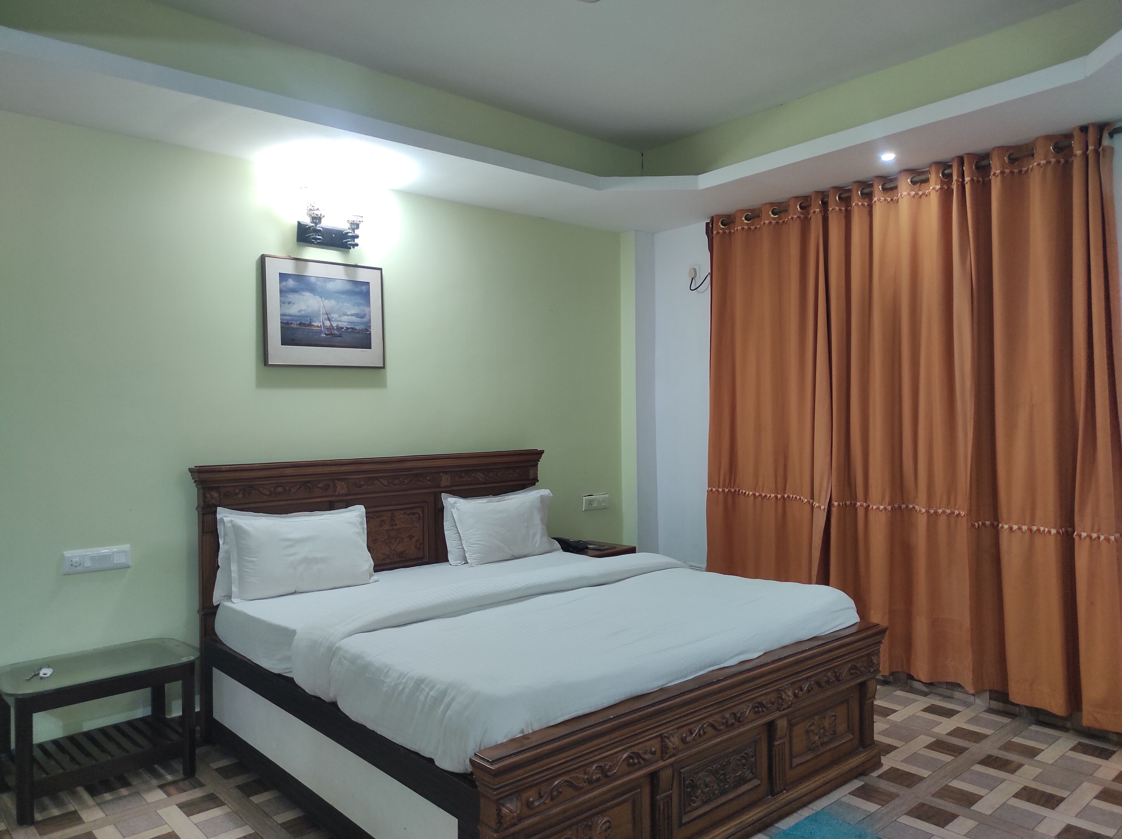 Una cama bien hecha con sábanas blancas, un cabecero de madera y una mesita de noche con una lámpara.