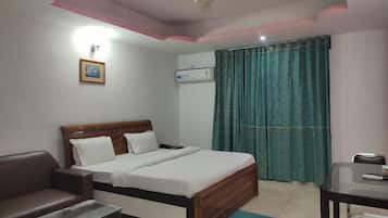 Un dormitorio con cama, escritorio, silla, ventilador de techo y ventana con cortinas.