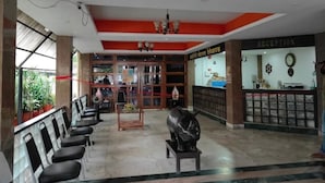 A reception area with a reception desk, a clock, and a statue. - Hotel Sanjivani Heritage (Dibrugarh)