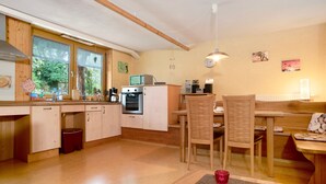 Eine moderne Küche mit Holzausstattung, einer Mikrowelle und einem Essbereich mit Tisch und Stühlen.