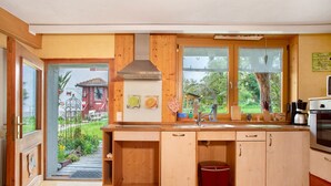 Eine Küche mit Holdekor-Schränken, einer Edelstahl-Dunstabzugshaube, einem Spülbecken und einem Fenster mit Blick auf einen Garten.