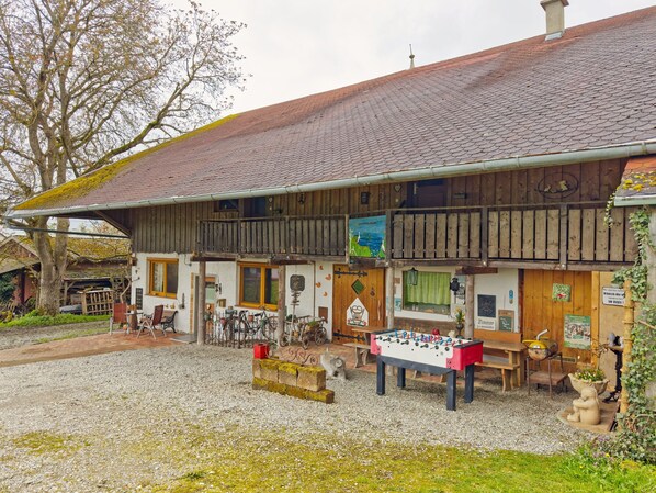 Ein traditionelles Holzhaus mit geneigtem Dach, einem Balkon mit Holzgeländern und einem Tischkicker im Vordergrund.