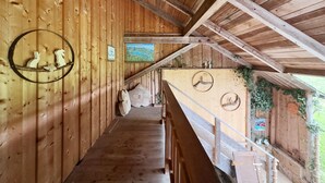 A wooden interior with a wooden staircase, a circular wooden decoration, and a view of the outdoors. - Apartment 'Schneckenhaus' with Shared Garden, Balcony and Wi-Fi (Ostrach- Waldbeuren)