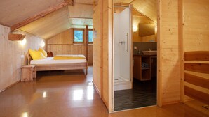 A wooden interior with a bed, a bathroom, and a small seating area. - Apartment 'Schneckenhaus' with Shared Garden, Balcony and Wi-Fi (Ostrach- Waldbeuren)