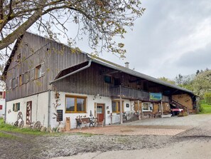 Ein rustikales Gebäude mit Holzfassade, Balkon und Sitzgelegenheit im Freien.