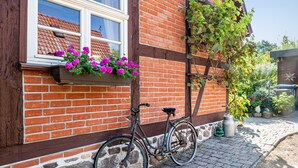 A bicycle parked against a brick wall with a window above it. - Holiday Apartment 'Fachwerkferienhaus' with Lake View, Terrace & Wi-Fi (Ulrichshusen)