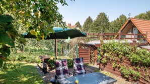 A patio with a table and chairs, a green umbrella, and a wooden fence. - Holiday Apartment 'Fachwerkferienhaus' with Lake View, Terrace & Wi-Fi (Ulrichshusen)