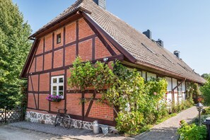 A traditional half-timbered house with a stone foundation, a bicycle, and a flower box. - Holiday Apartment 'Fachwerkferienhaus' with Lake View, Terrace & Wi-Fi (Ulrichshusen)
