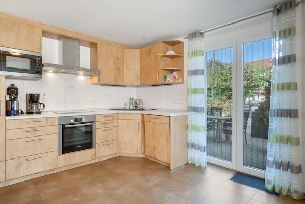 A modern kitchen with wooden cabinets, a built-in oven, and a microwave.