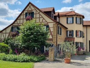 Ein traditionelles Fachwerkhäuschen mit Garten, Tor und Bank.