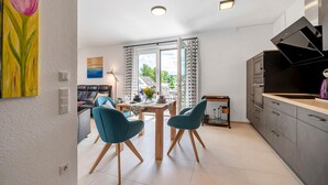 A modern kitchen with a built-in oven, a dining area with a table and chairs, and a view through the glass doors. - Holiday Apartment 'Im Naturpark Rhein-Westerwald' with Private Terrace and Wi-Fi (Puderbach)