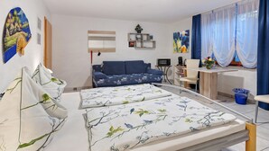 Ein Schlafzimmer mit einem Bett, einem Schlafsofa, einem Schreibtisch und einem Stuhl.