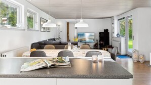 A modern kitchen with a dining area, large windows, and a built-in stove.
