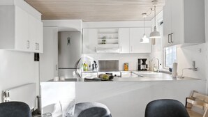 A modern kitchen with white cabinetry, a central island, and pendant lighting.