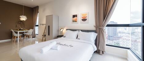 Una habitación de hotel moderna con una cama grande, un área de comedor y vistas a la ciudad.