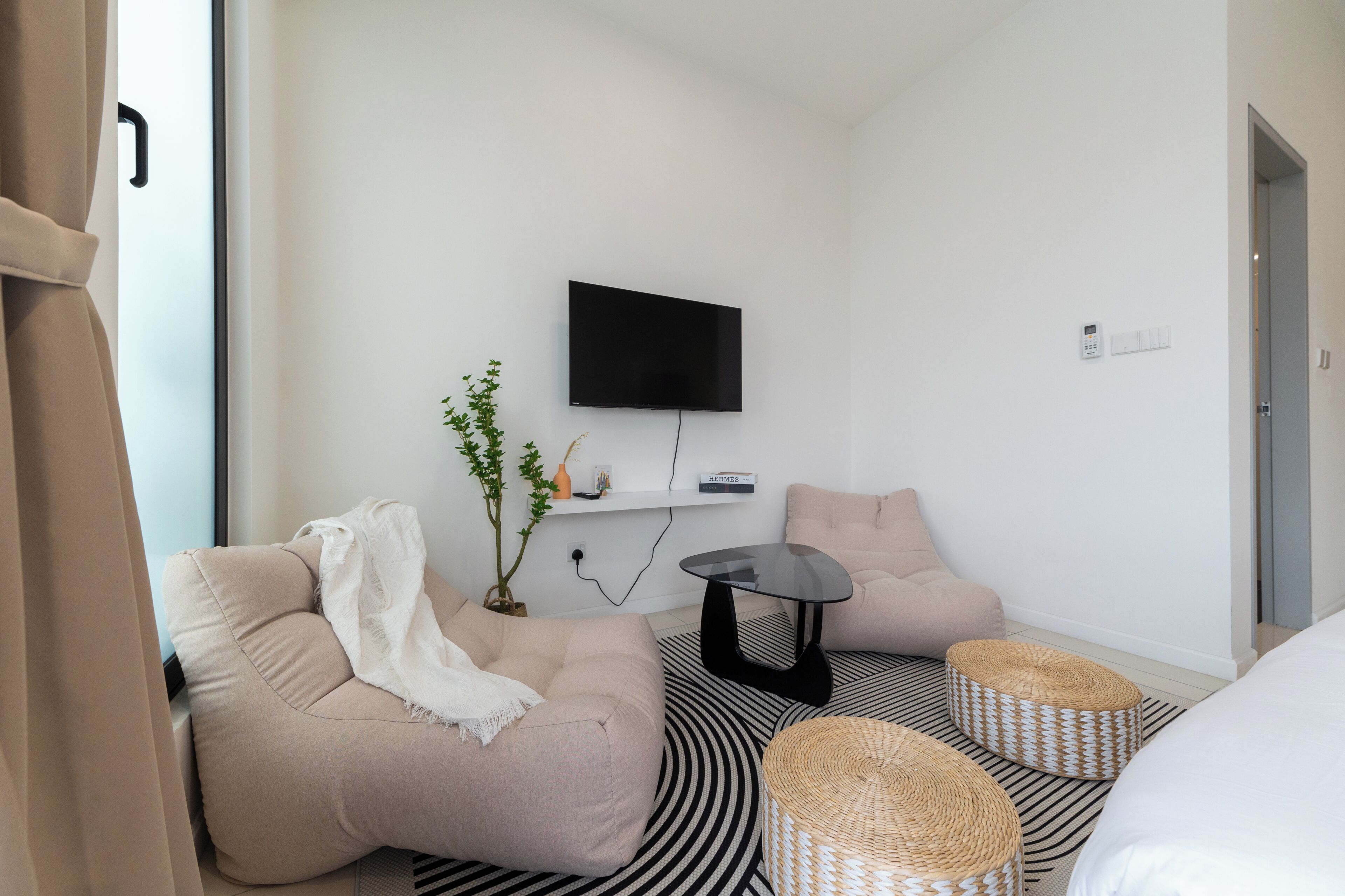 Ein modernes Zimmer mit einer Couch, einem kleinen Tisch, einem Fernseher und einer Pflanze.