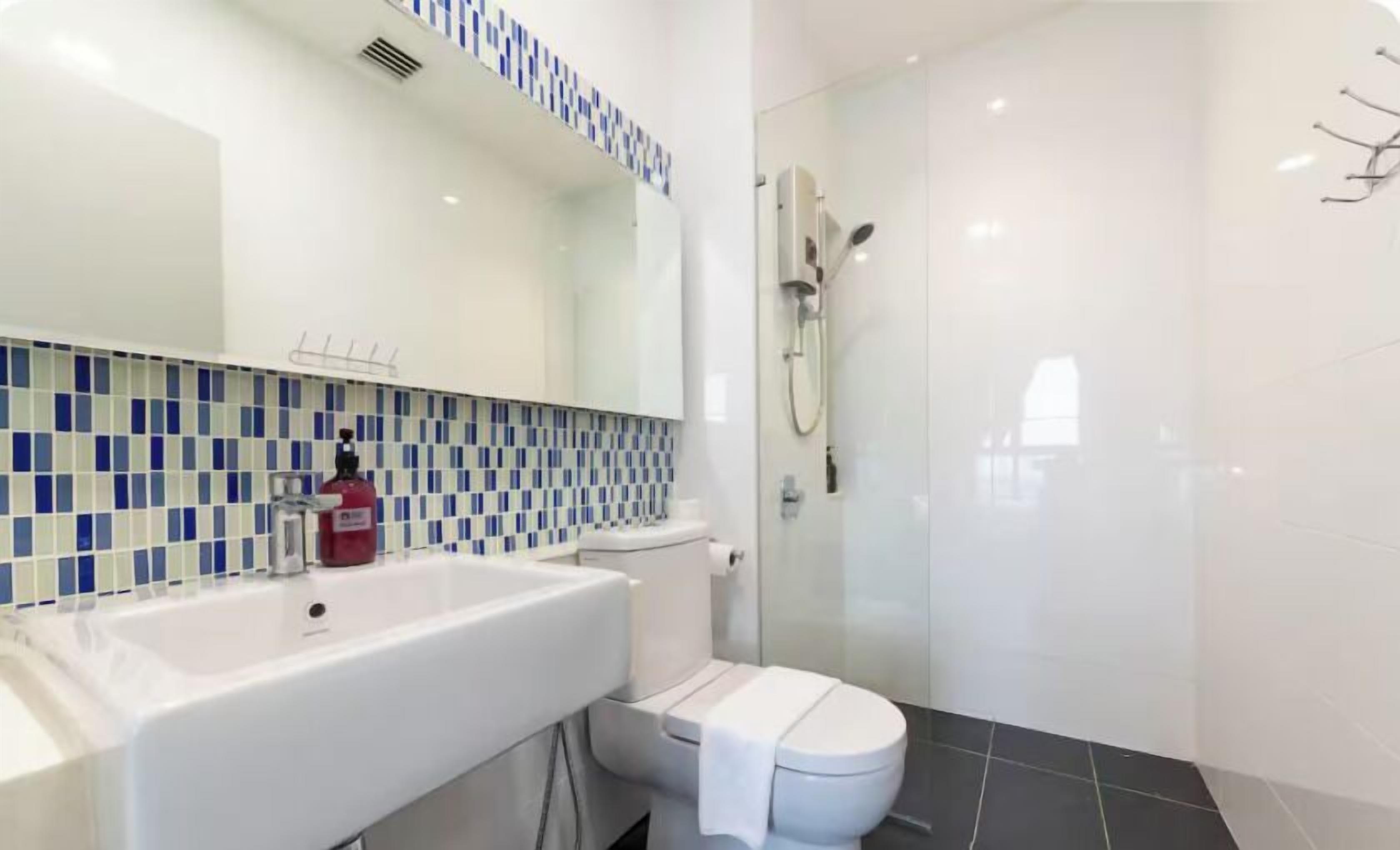 A modern bathroom with a white sink, a toilet, and a glass-enclosed shower.