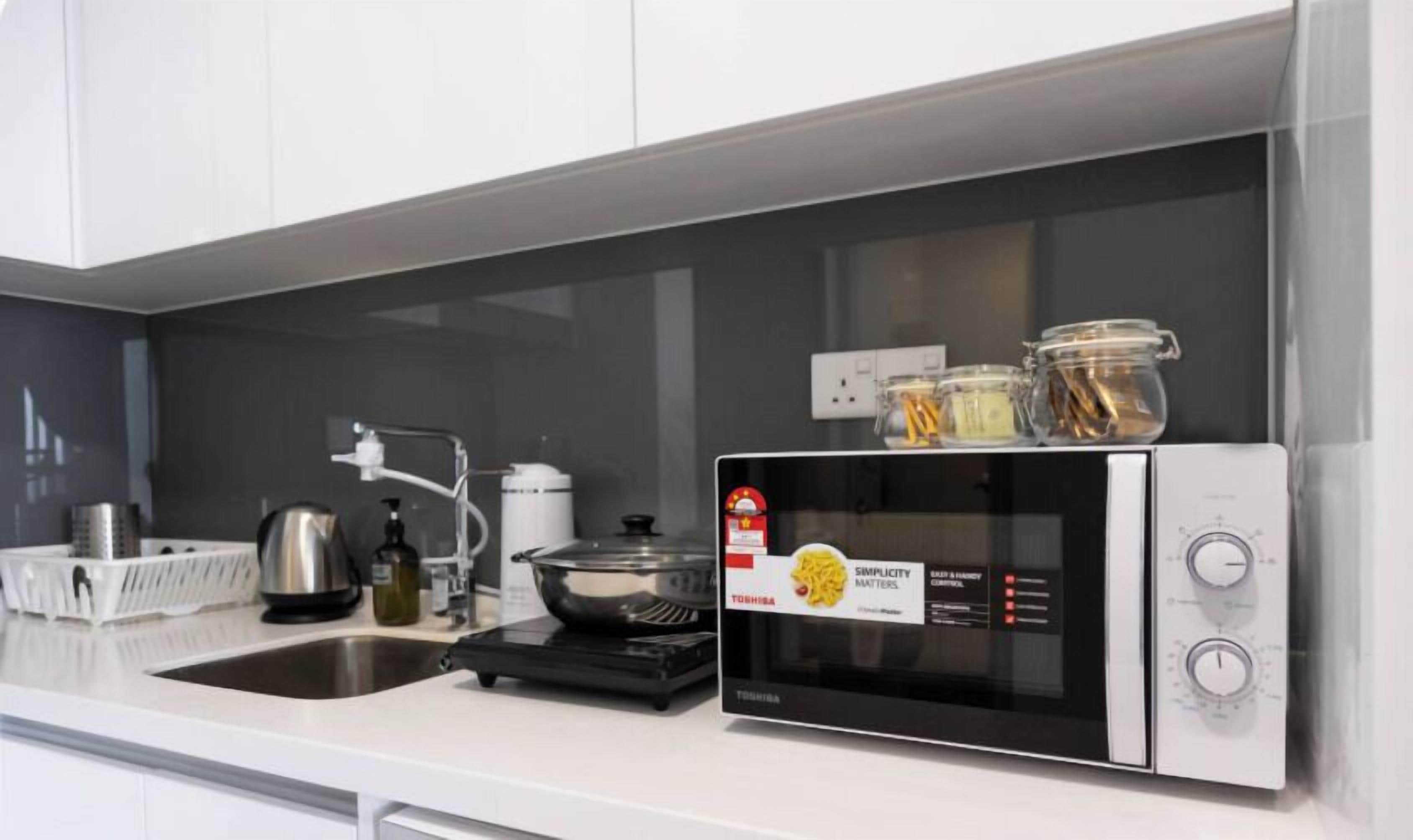 Uma cozinha moderna com micro-ondas embutido, pia de aço inoxidável e diversos eletrodomésticos.