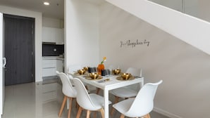 Un comedor moderno con una mesa blanca, cuatro sillas y una pared decorativa con una frase.