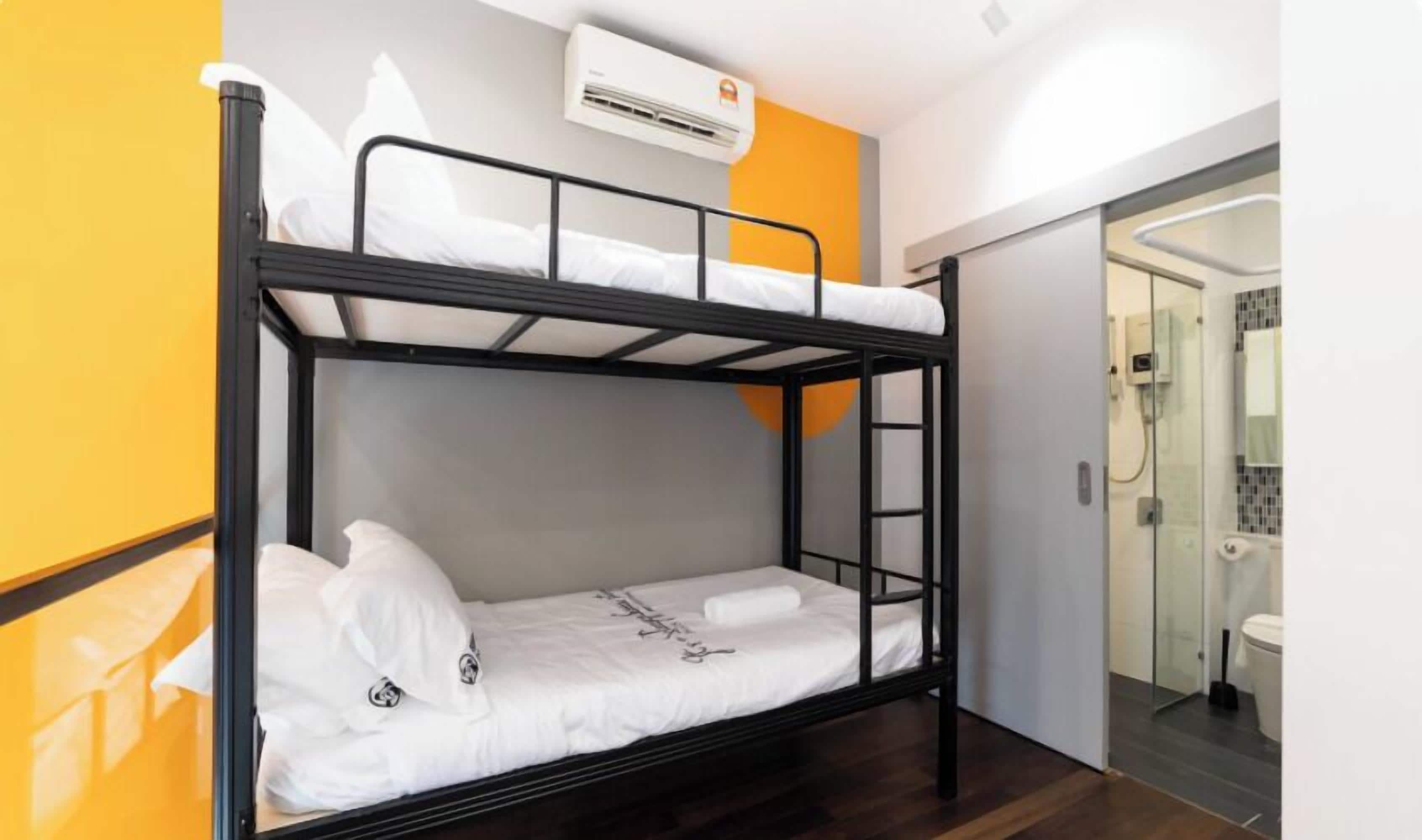 A bunk bed in a room with a glass shower door, a white air conditioning unit, and a yellow accent wall.