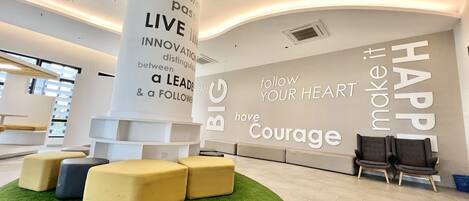 Un interior moderno con una pared decorativa motivacional, una zona de estar y vistas al exterior.