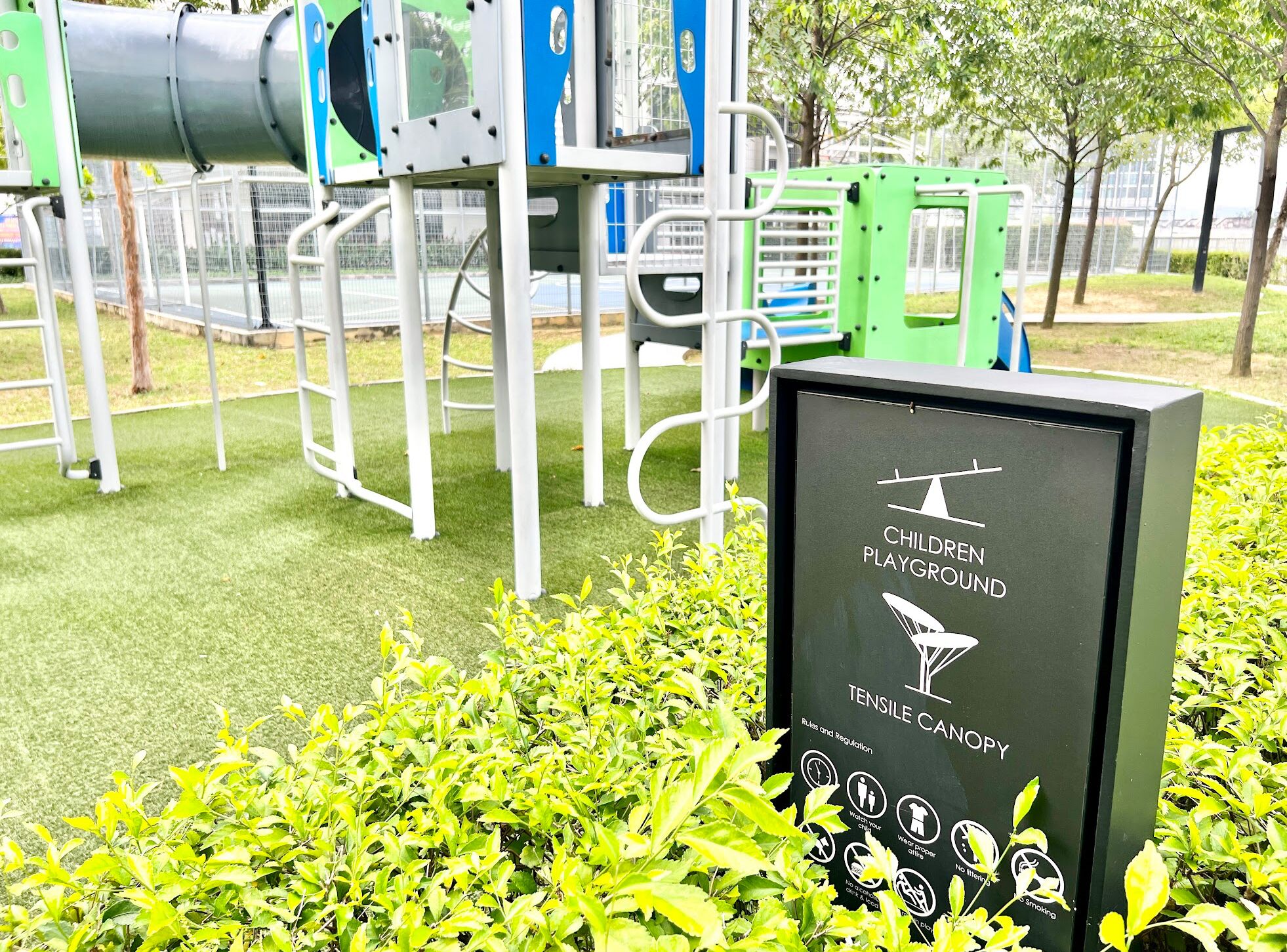 Un parque infantil con un cartel que indica que es un área de juegos para niños y un letrero tensado.